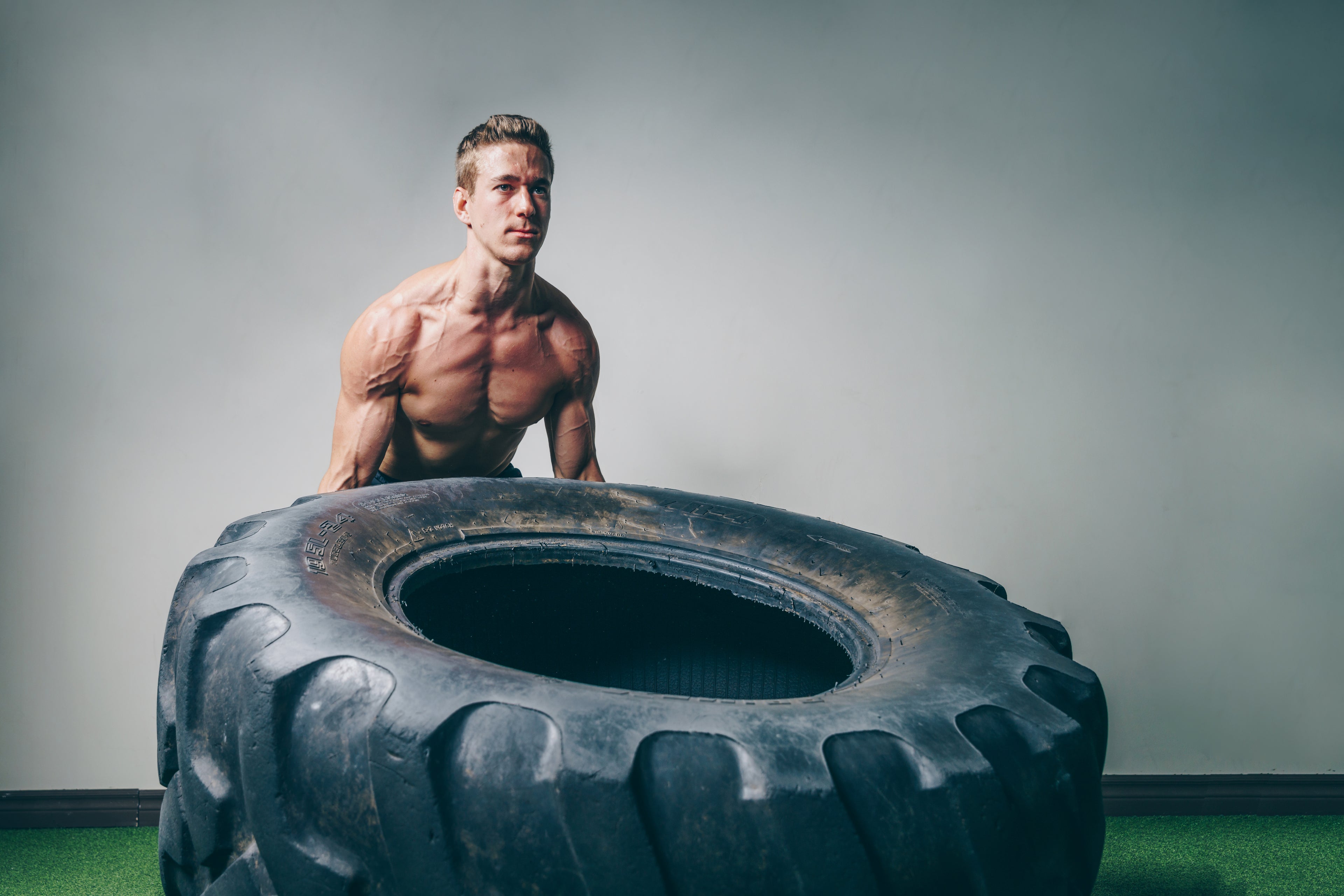 Athlete lifting heavy tyre in STRYK training gear - Hyrox style strength and endurance workout