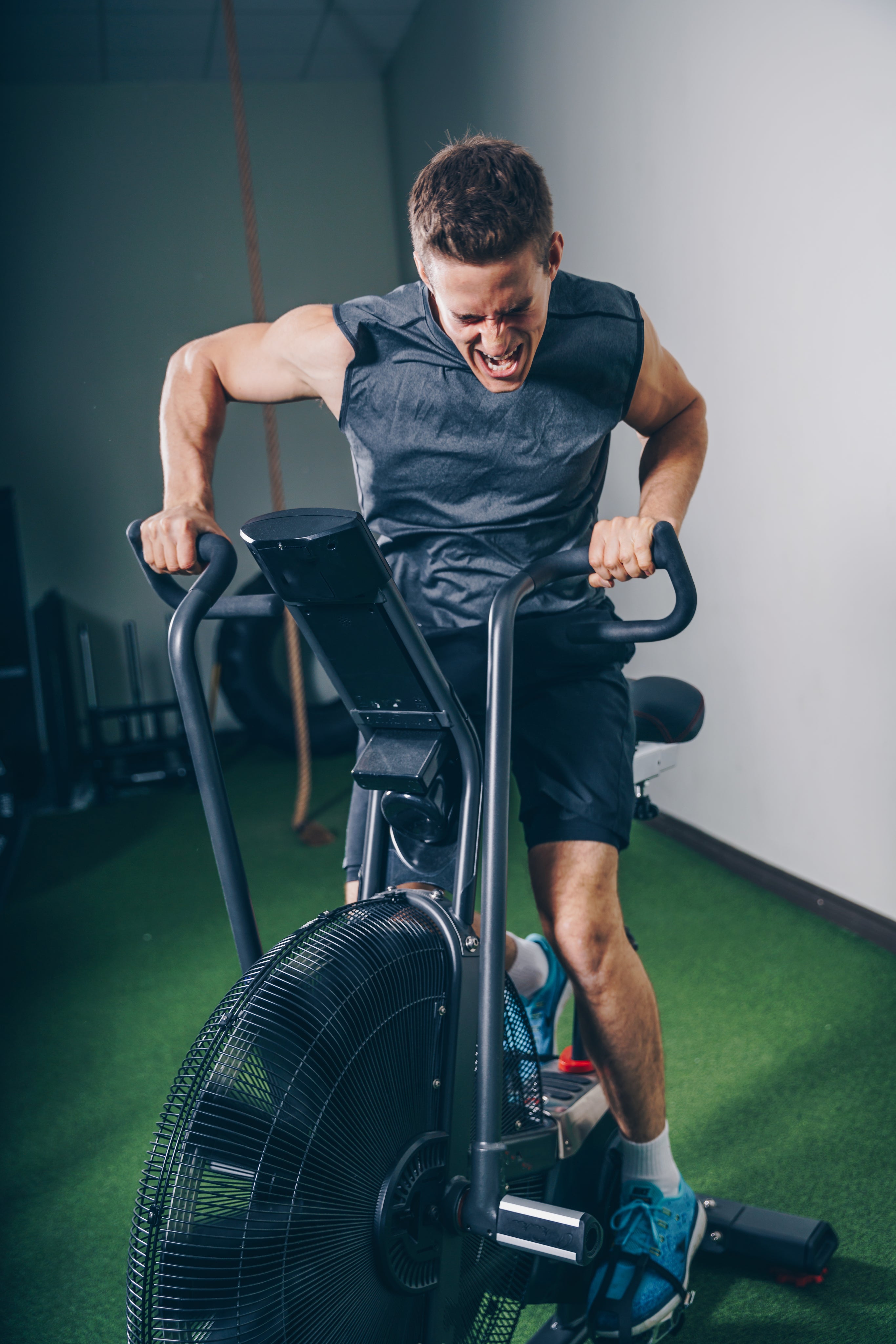 Athlete wearing STRYK gym apparel pushing hard on assault bike - tactical fitness clothing for strength and endurance