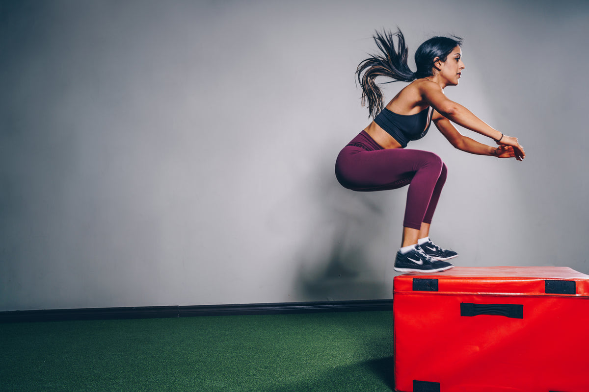 Athlete performing explosive box jumps in STRYK gym apparel - power and conditioning training.